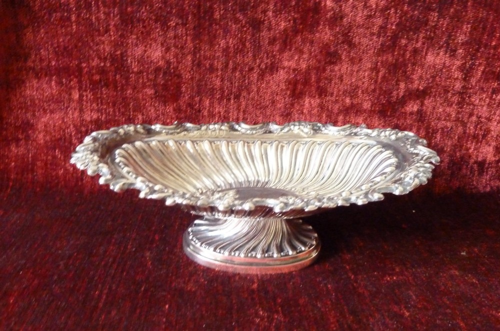An oval Victorian sterling silver bonbon dish featuring a fluted body, scrollwork rim, and London hallmarks. View VIII