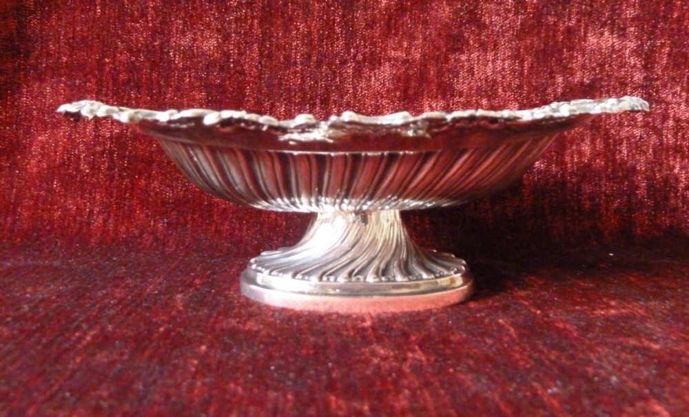 An oval Victorian sterling silver bonbon dish featuring a fluted body, scrollwork rim, and London hallmarks. View IX