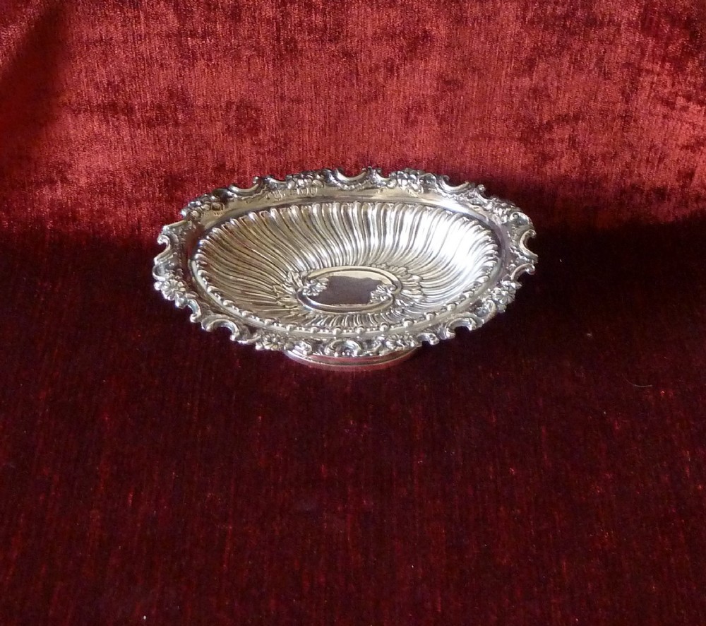 An oval Victorian sterling silver bonbon dish featuring a fluted body, scrollwork rim, and London hallmarks. View X