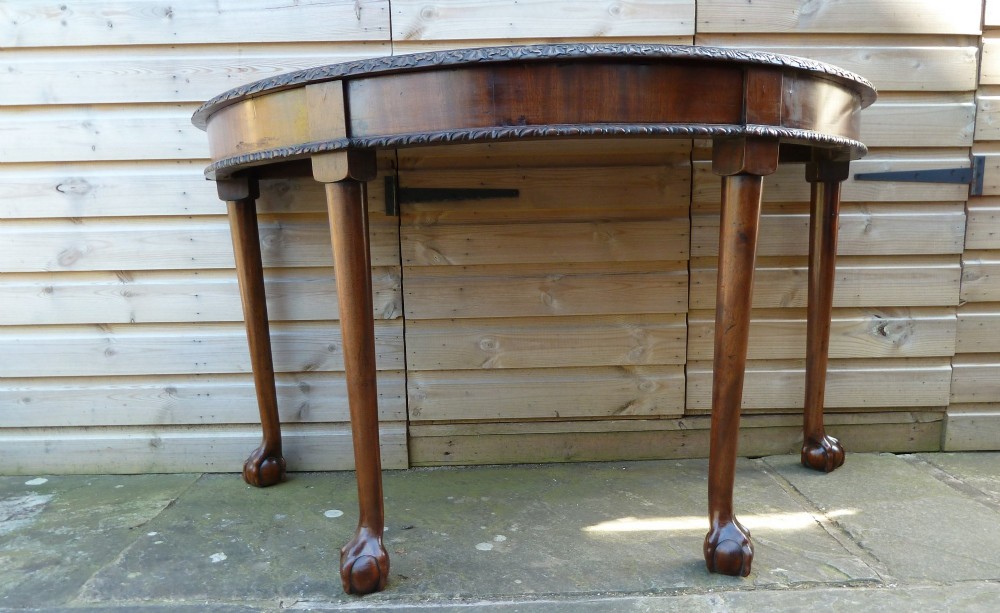 A pair of late 19th-century mahogany demilune console tables featuring carved aprons and cabriole legs with claw-and-ball feet. View VI