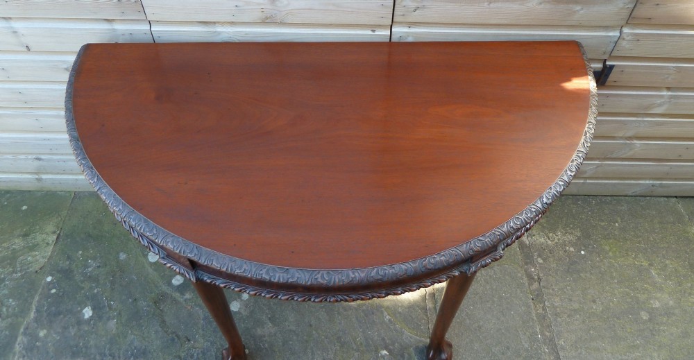 A pair of late 19th-century mahogany demilune console tables featuring carved aprons and cabriole legs with claw-and-ball feet. View IX