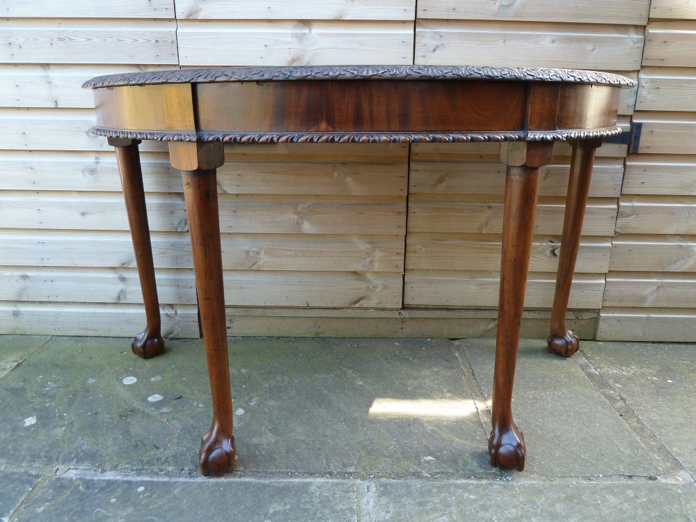 A pair of late 19th-century mahogany demilune console tables featuring carved aprons and cabriole legs with claw-and-ball feet. View XI