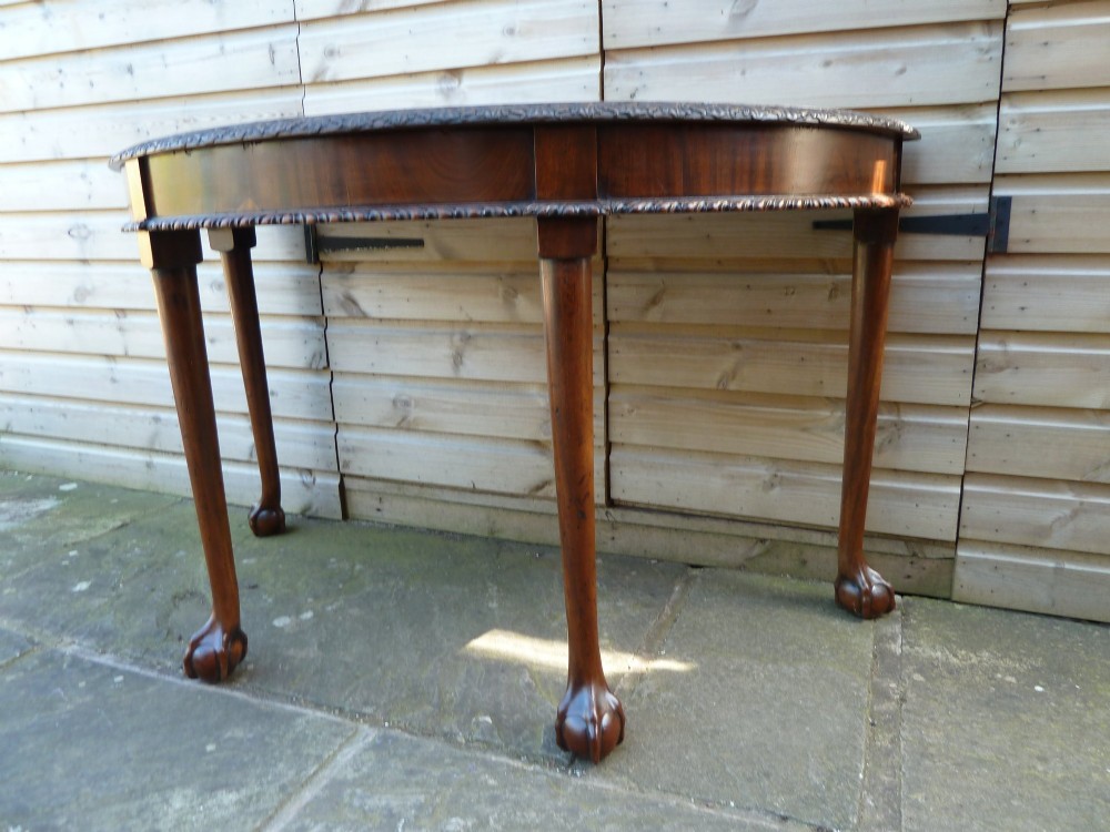 A pair of late 19th-century mahogany demilune console tables featuring carved aprons and cabriole legs with claw-and-ball feet. View XII
