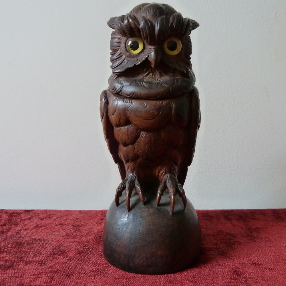 A detailed hand-carved dark wood owl inkwell featuring inset yellow glass eyes perched upon a rounded wooden dome base.