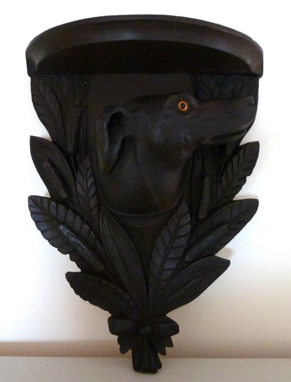 A dark brown hand-carved wooden wall bracket featuring a dog head surrounded by carved leaves below a small rounded shelf. View II