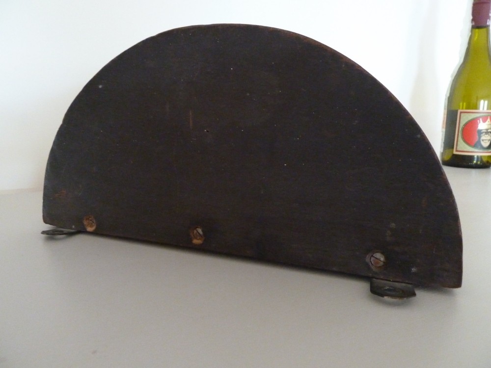 A dark brown hand-carved wooden wall bracket featuring a dog head surrounded by carved leaves below a small rounded shelf. View V