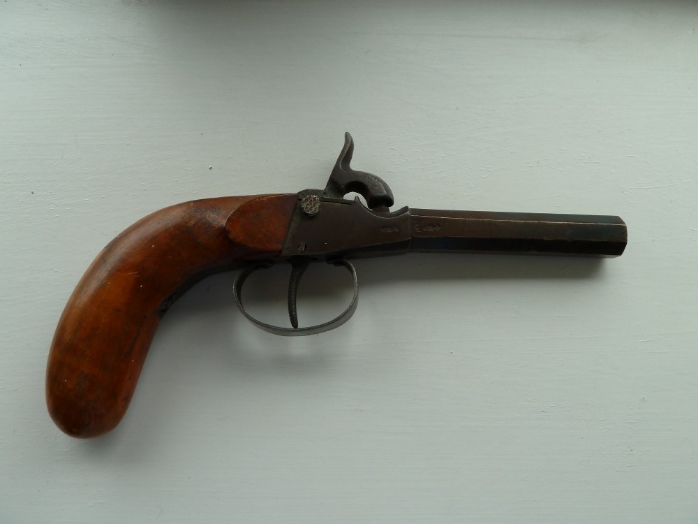 A 19th-century percussion pocket pistol featuring an octagonal steel barrel, iron trigger guard, and smooth curved wooden grip.