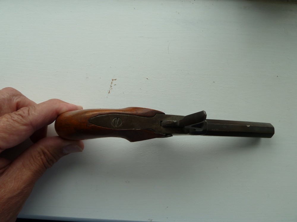 A 19th-century percussion pocket pistol featuring an octagonal steel barrel, iron trigger guard, and smooth curved wooden grip. View III