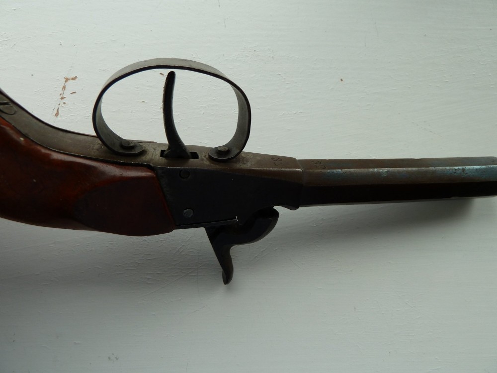 A 19th-century percussion pocket pistol featuring an octagonal steel barrel, iron trigger guard, and smooth curved wooden grip. View V