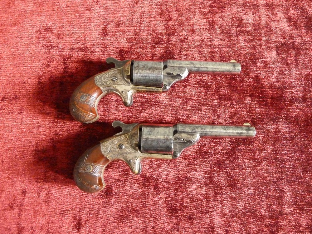 A pair of 19th-century American rimfire pocket revolvers featuring engraved metal frames, cylindrical barrels, and smooth wood grips.