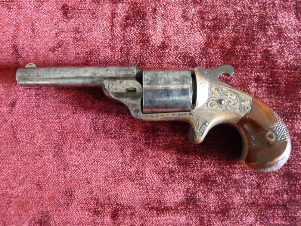 A pair of 19th-century American rimfire pocket revolvers featuring engraved metal frames, cylindrical barrels, and smooth wood grips. View V