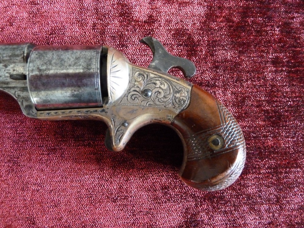 A pair of 19th-century American rimfire pocket revolvers featuring engraved metal frames, cylindrical barrels, and smooth wood grips. View VI