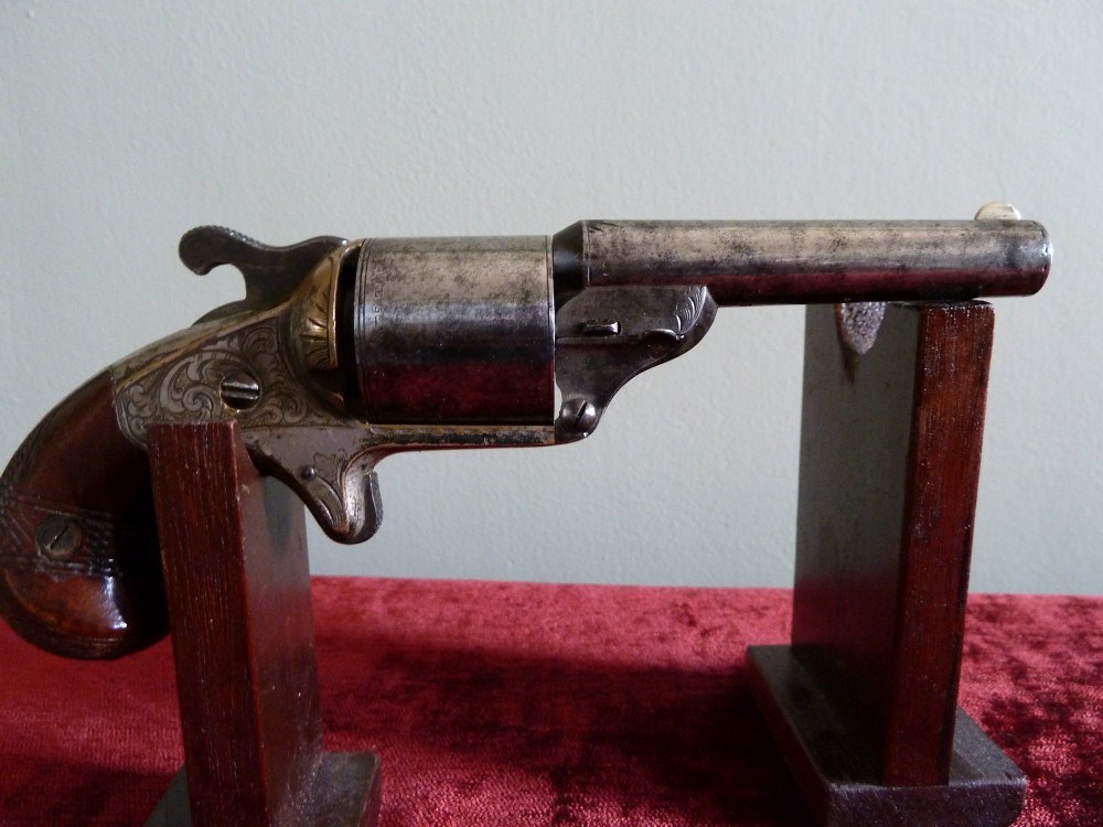 A pair of 19th-century American rimfire pocket revolvers featuring engraved metal frames, cylindrical barrels, and smooth wood grips. View VII