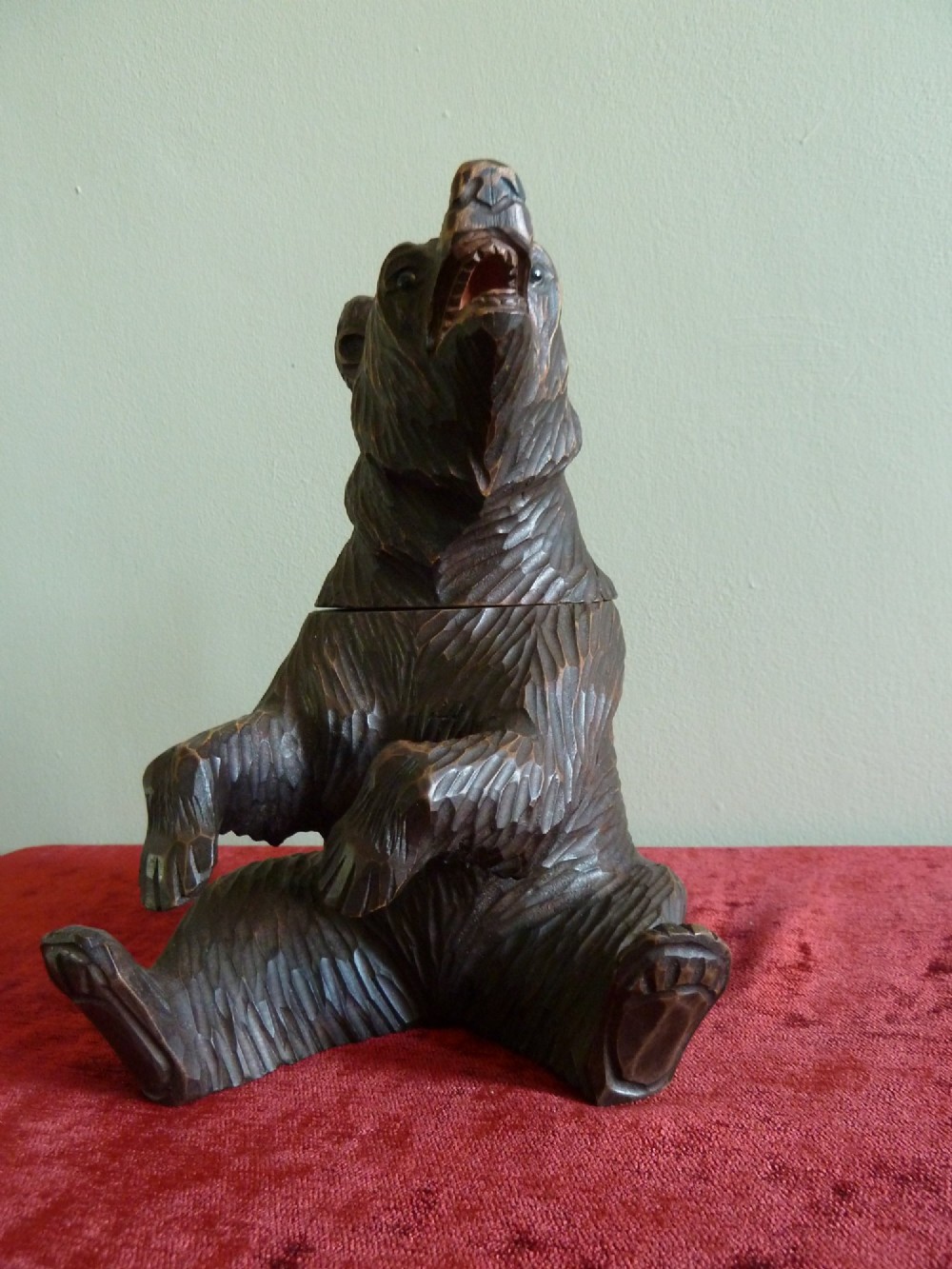 A carved dark brown wooden Black Forest bear depicted in a seated position with open jaws, featuring a removable head function. View IX