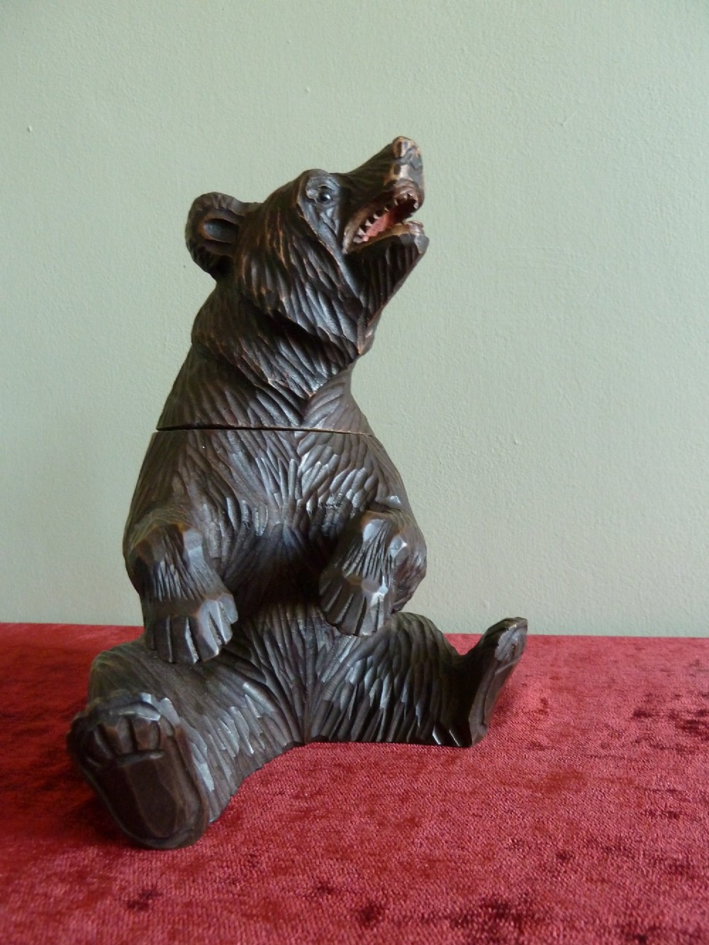 A carved dark brown wooden Black Forest bear depicted in a seated position with open jaws, featuring a removable head function. View X