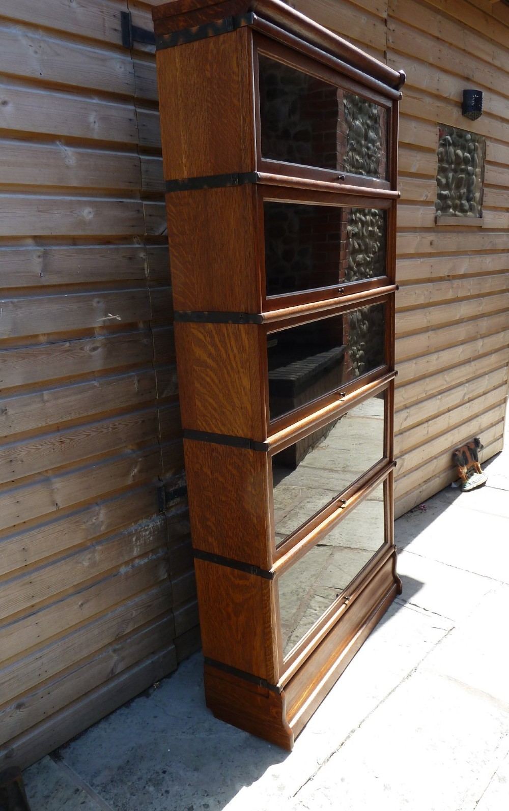 A five-tier golden oak Globe Wernicke modular bookcase featuring glazed up-and-over doors and brass knob handles. View III