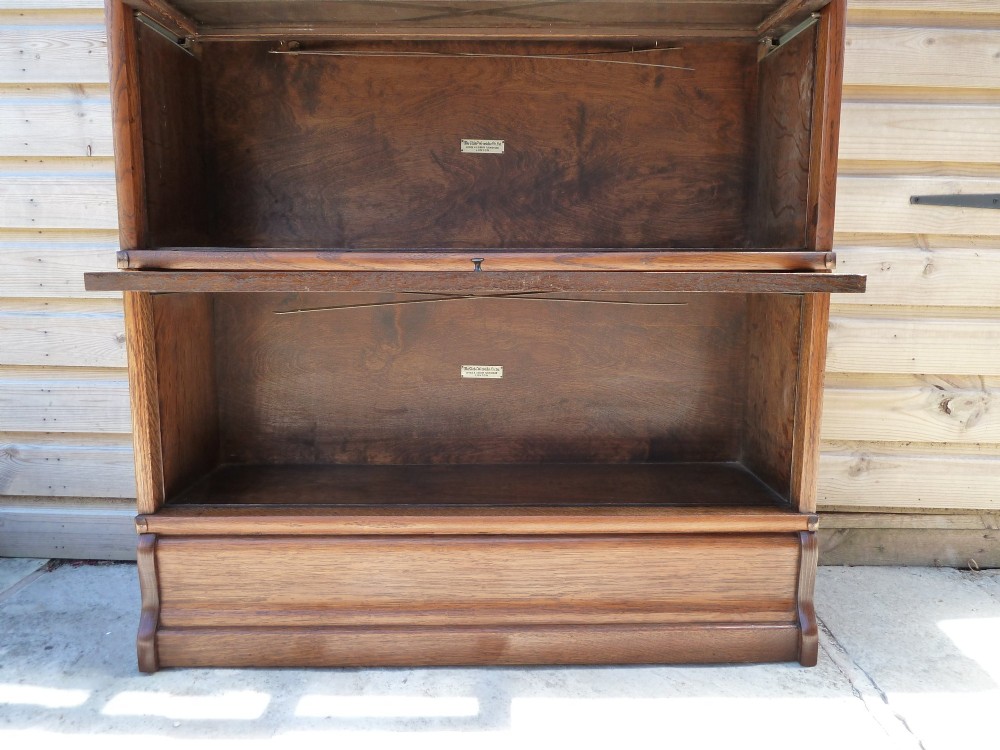 A five-tier golden oak Globe Wernicke modular bookcase featuring glazed up-and-over doors and brass knob handles. View IX