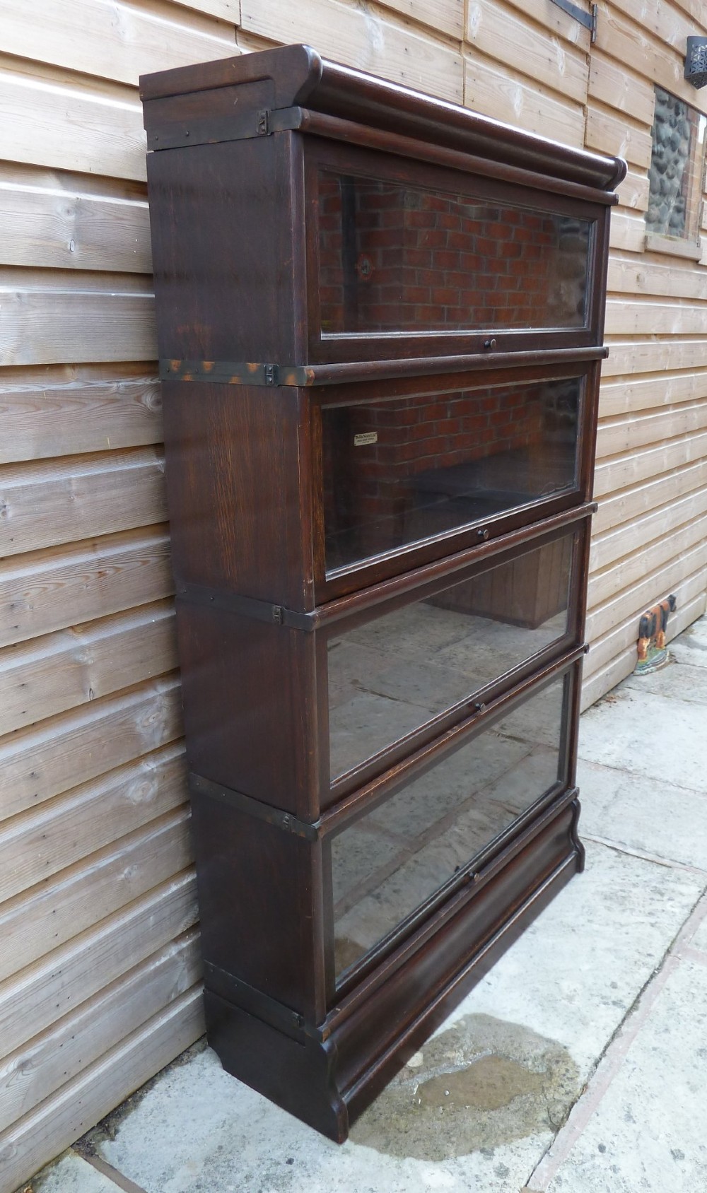 A four-tier dark oak Globe Wernicke sectional bookcase featuring glazed lift-up doors and a plinth base. View II