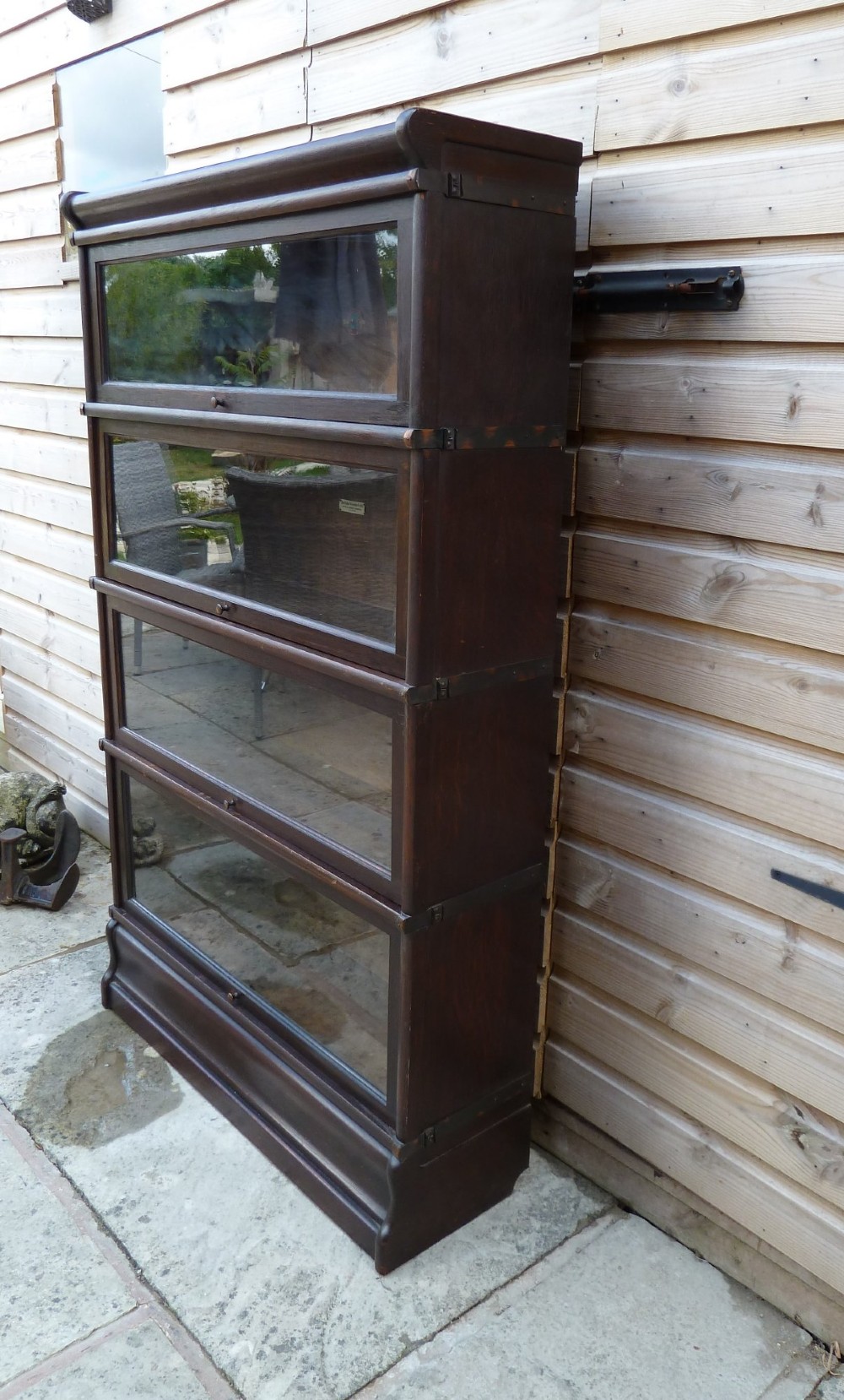 A four-tier dark oak Globe Wernicke sectional bookcase featuring glazed lift-up doors and a plinth base. View III