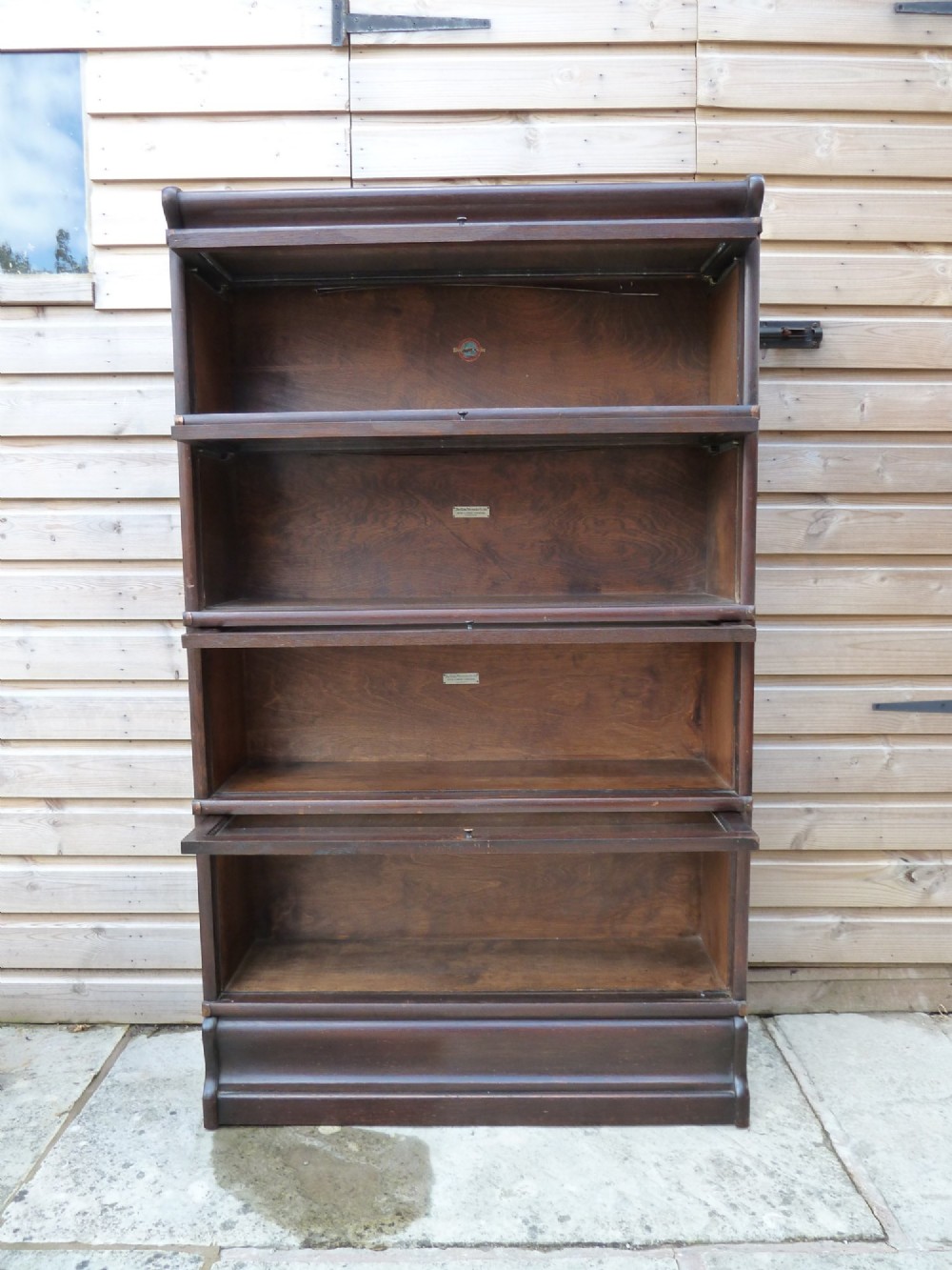 A four-tier dark oak Globe Wernicke sectional bookcase featuring glazed lift-up doors and a plinth base. View V