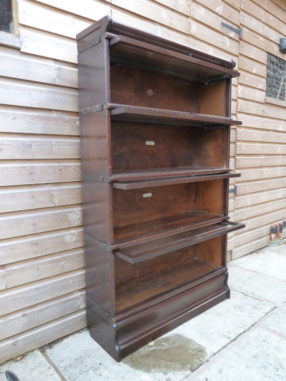 A four-tier dark oak Globe Wernicke sectional bookcase featuring glazed lift-up doors and a plinth base. View VII
