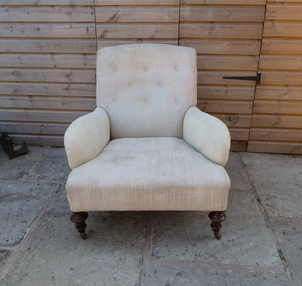 A low-slung, cream fabric upholstered armchair with a buttoned backrest, padded scroll arms, and dark turned legs on castors. View II