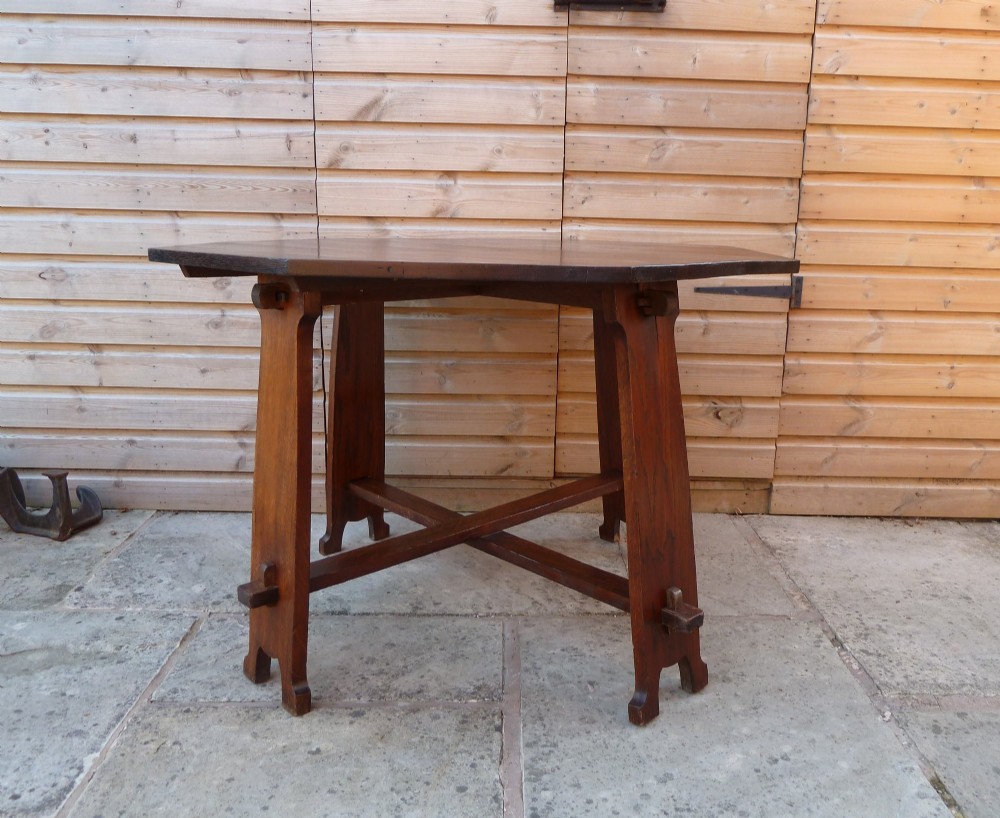 An octagonal solid dark oak Arts and Crafts centre table featuring an exposed tusk tenon cross-stretcher base. View II