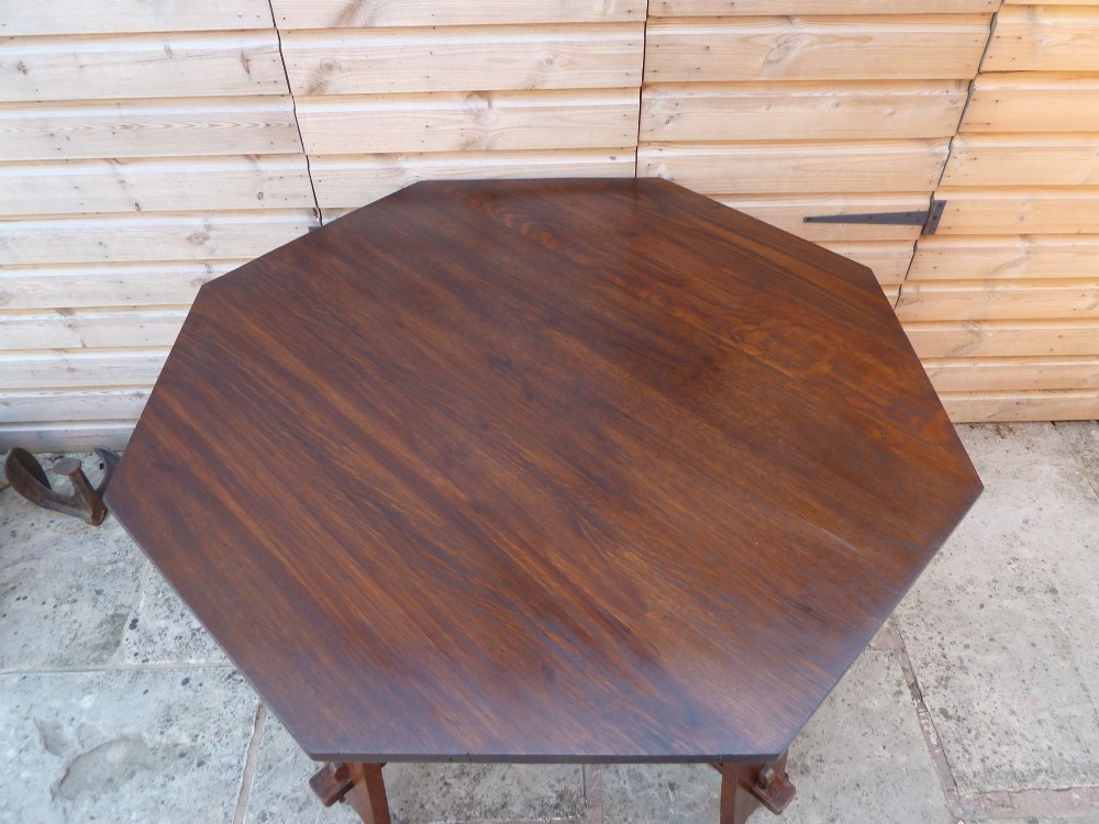 An octagonal solid dark oak Arts and Crafts centre table featuring an exposed tusk tenon cross-stretcher base. View III
