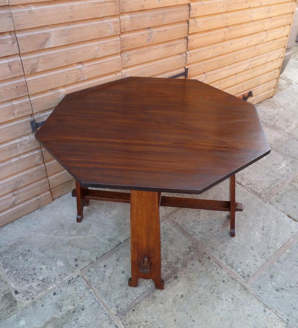 An octagonal solid dark oak Arts and Crafts centre table featuring an exposed tusk tenon cross-stretcher base. View V