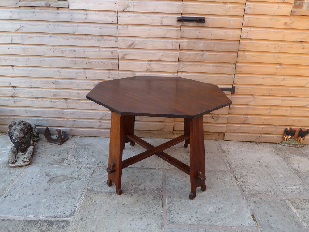An octagonal solid dark oak Arts and Crafts centre table featuring an exposed tusk tenon cross-stretcher base. View VI
