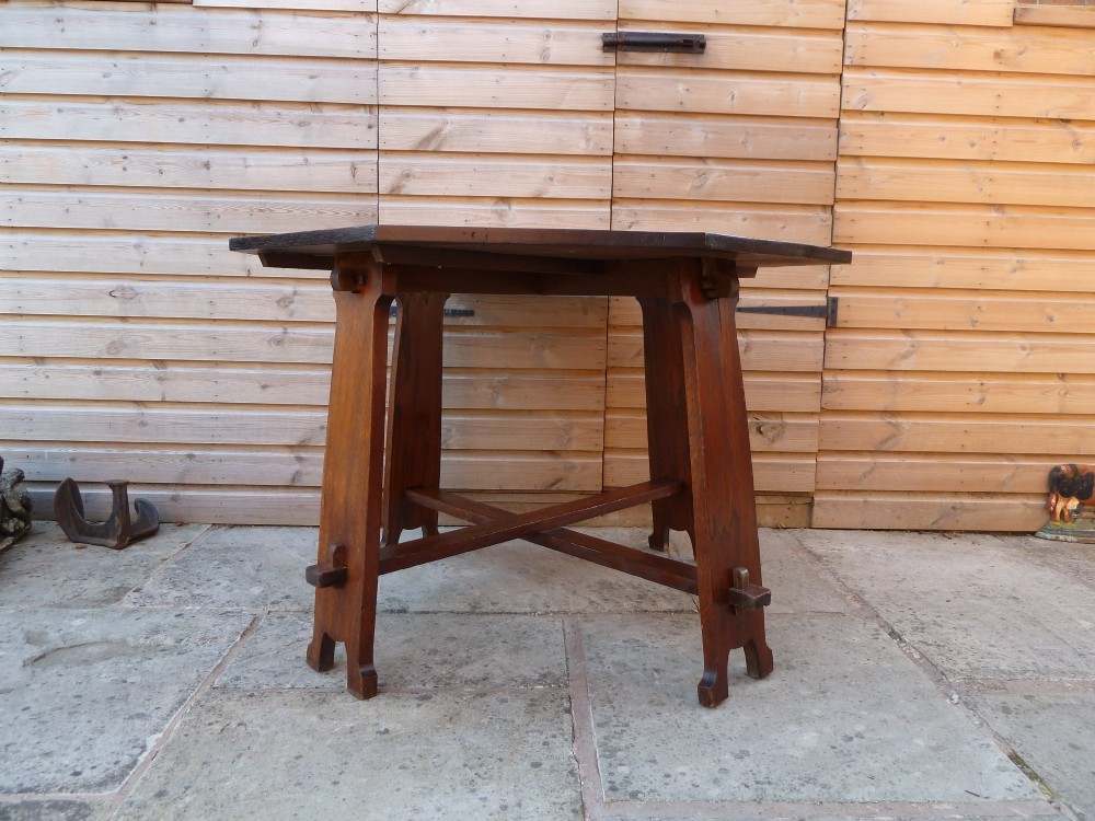 An octagonal solid dark oak Arts and Crafts centre table featuring an exposed tusk tenon cross-stretcher base. View VII