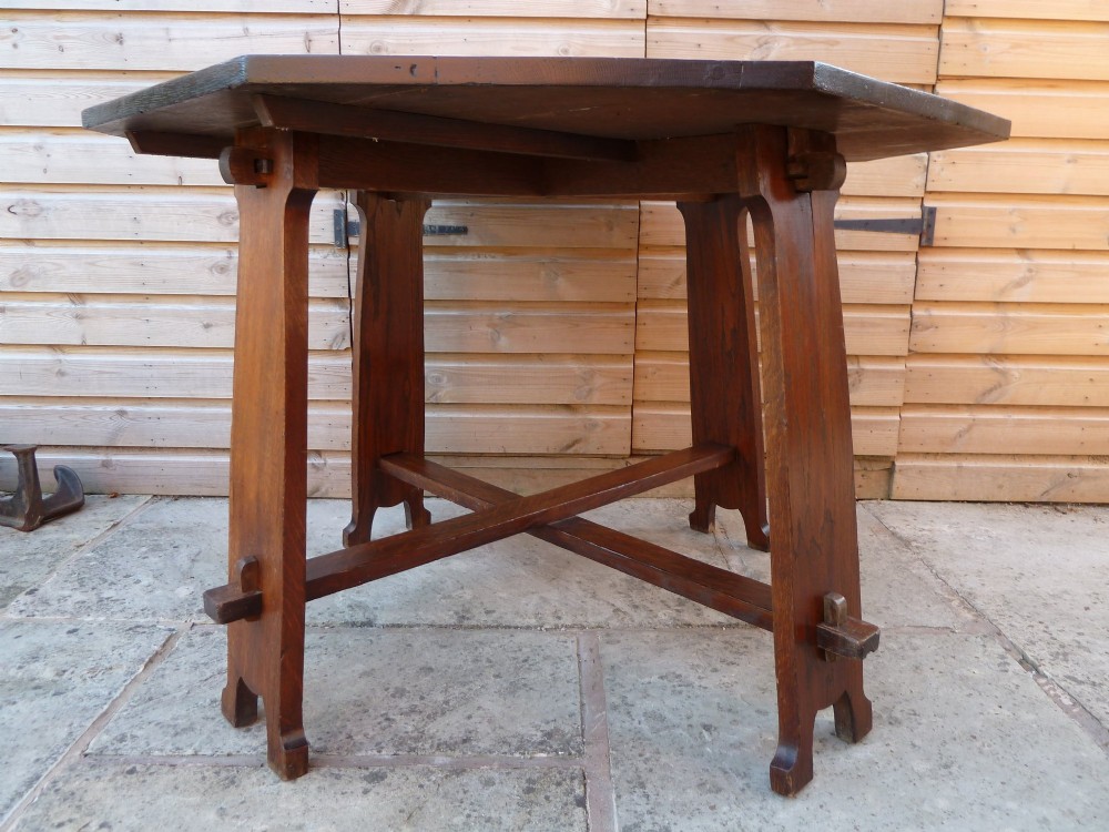 An octagonal solid dark oak Arts and Crafts centre table featuring an exposed tusk tenon cross-stretcher base. View VIII