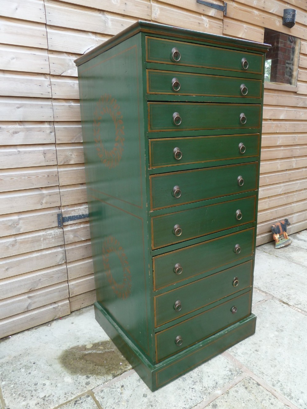 A tall dark green painted pine office chest featuring eight drawers with brass ring handles and gold pinstripe lining. View II