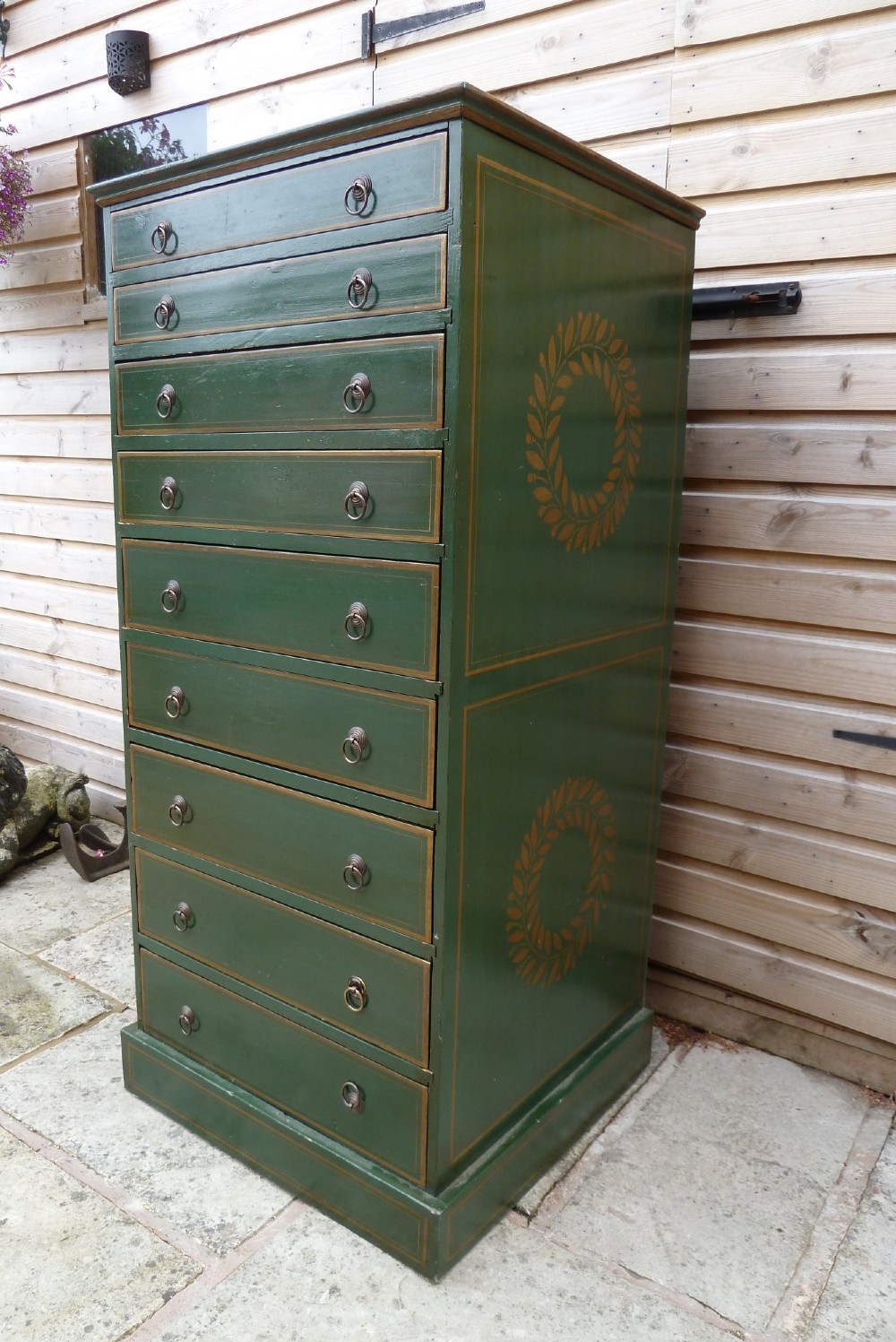 A tall dark green painted pine office chest featuring eight drawers with brass ring handles and gold pinstripe lining. View III
