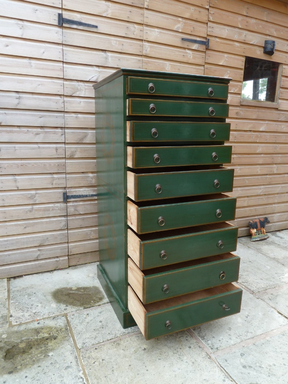 A tall dark green painted pine office chest featuring eight drawers with brass ring handles and gold pinstripe lining. View VIII