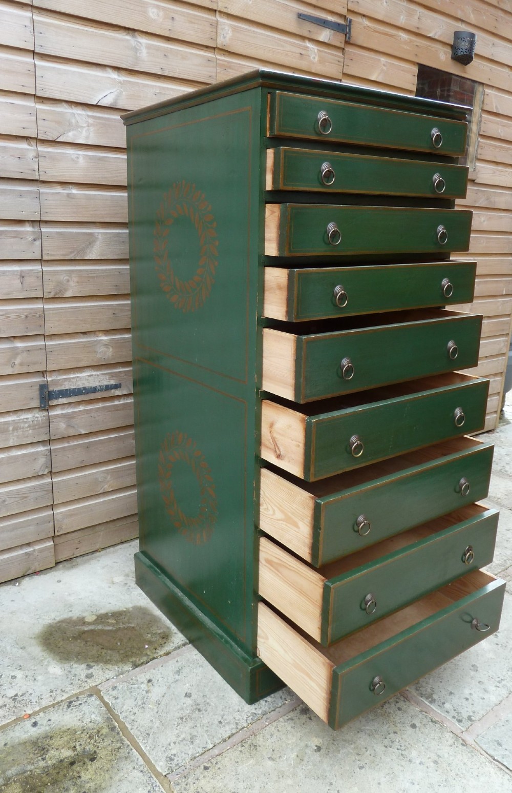 A tall dark green painted pine office chest featuring eight drawers with brass ring handles and gold pinstripe lining. View IX
