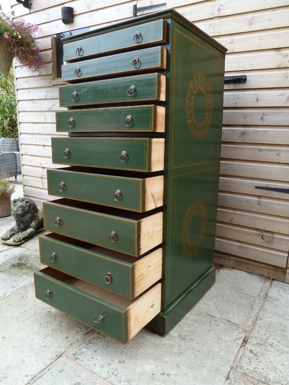 A tall dark green painted pine office chest featuring eight drawers with brass ring handles and gold pinstripe lining. View X