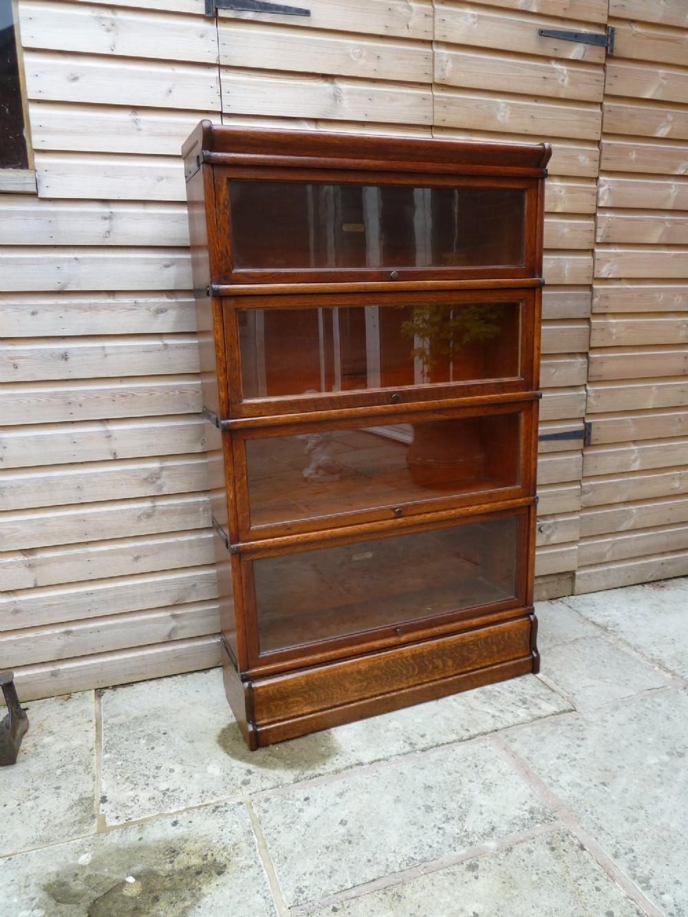 A four-tier medium oak Globe Wernicke sectional bookcase featuring glass up-and-over doors, a moulded top cornice, and a plinth base. View II