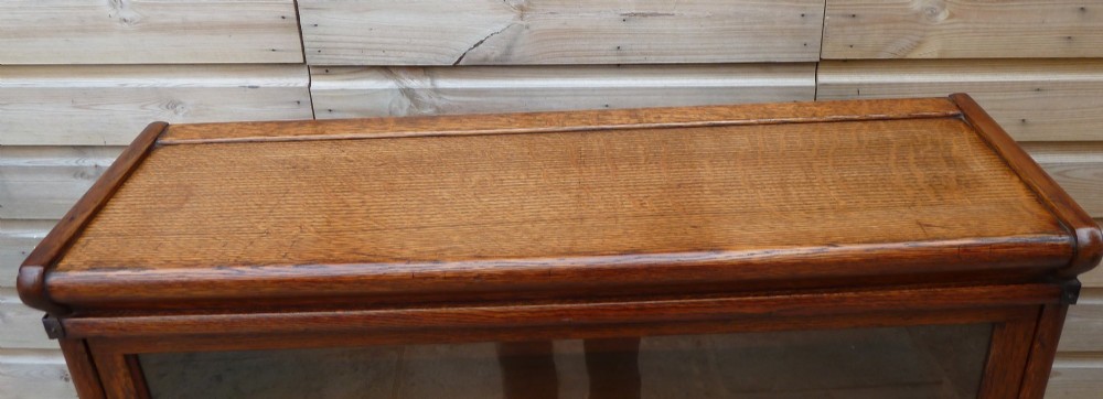 A four-tier medium oak Globe Wernicke sectional bookcase featuring glass up-and-over doors, a moulded top cornice, and a plinth base. View V