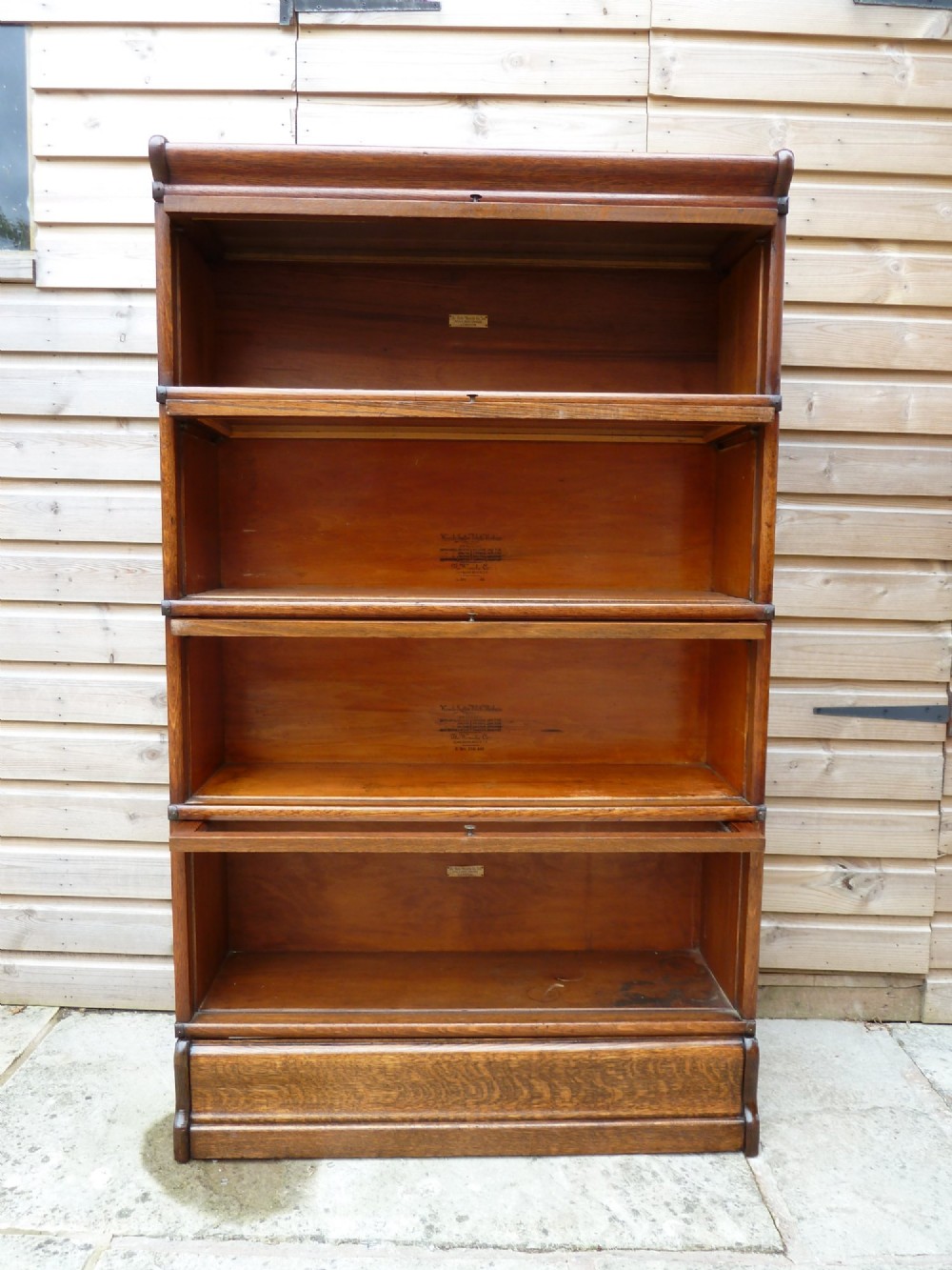 A four-tier medium oak Globe Wernicke sectional bookcase featuring glass up-and-over doors, a moulded top cornice, and a plinth base. View VI