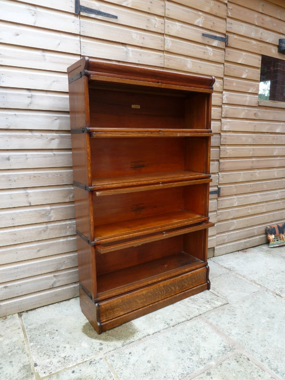 A four-tier medium oak Globe Wernicke sectional bookcase featuring glass up-and-over doors, a moulded top cornice, and a plinth base. View VII