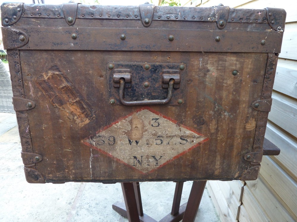 An open 19th-century flat-top steamer trunk featuring a brown striped canvas exterior, brass hardware, wood slatted bindings, and a cream quilted fabric interior lid lining. View VI