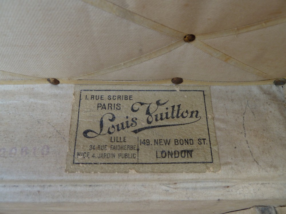 An open 19th-century flat-top steamer trunk featuring a brown striped canvas exterior, brass hardware, wood slatted bindings, and a cream quilted fabric interior lid lining. View XI