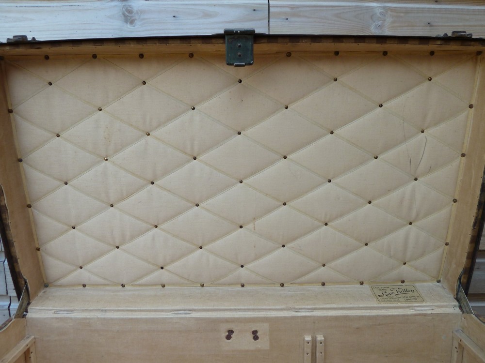 An open 19th-century flat-top steamer trunk featuring a brown striped canvas exterior, brass hardware, wood slatted bindings, and a cream quilted fabric interior lid lining. View XIII