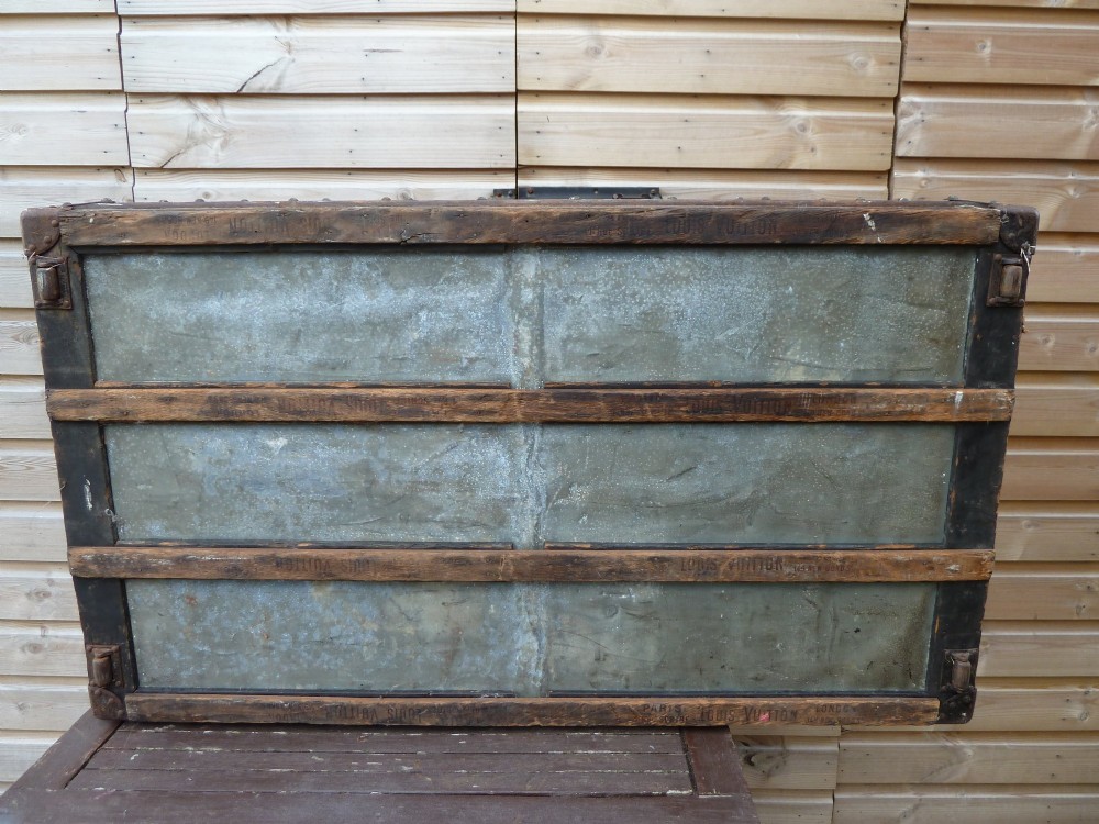 An open 19th-century flat-top steamer trunk featuring a brown striped canvas exterior, brass hardware, wood slatted bindings, and a cream quilted fabric interior lid lining. View XV