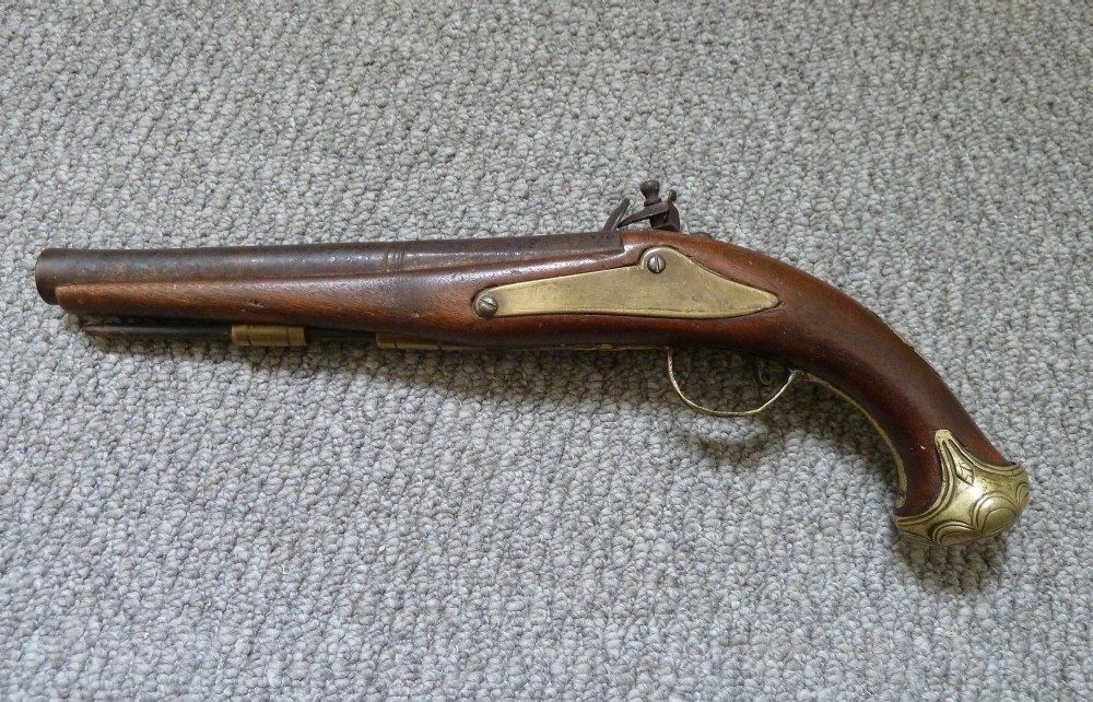 An 18th-century flintlock pistol featuring a carved dark walnut stock, engraved brass butt cap, brass ramrod pipes, and an iron lock mechanism. View II
