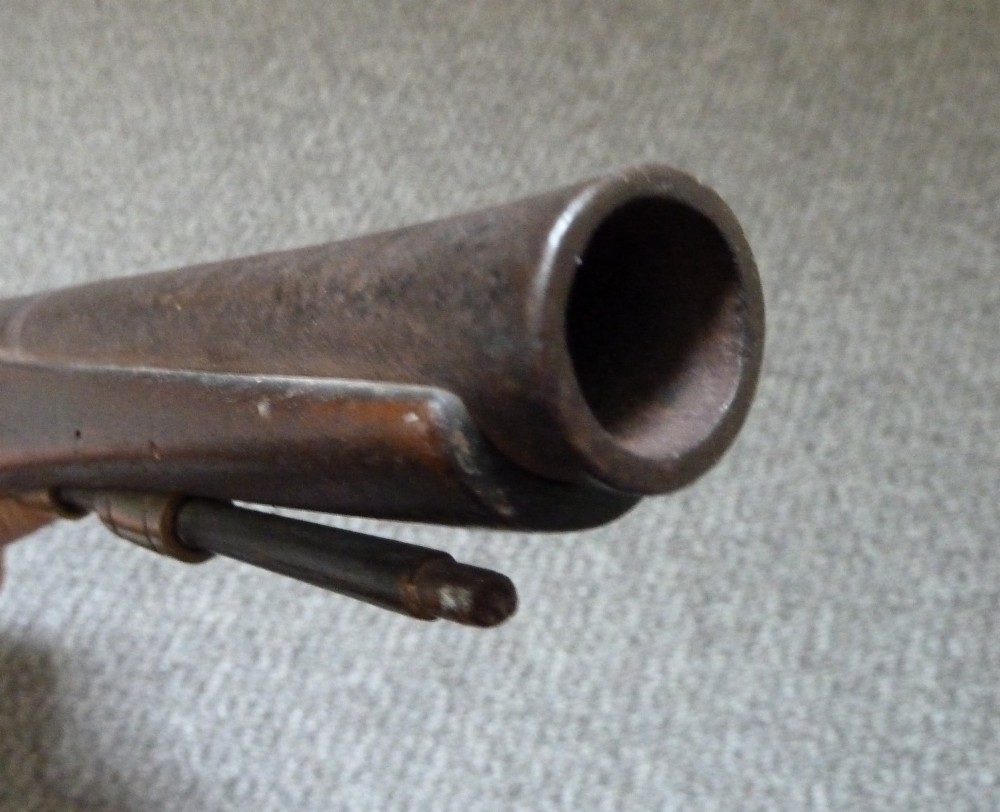 An 18th-century flintlock pistol featuring a carved dark walnut stock, engraved brass butt cap, brass ramrod pipes, and an iron lock mechanism. View X