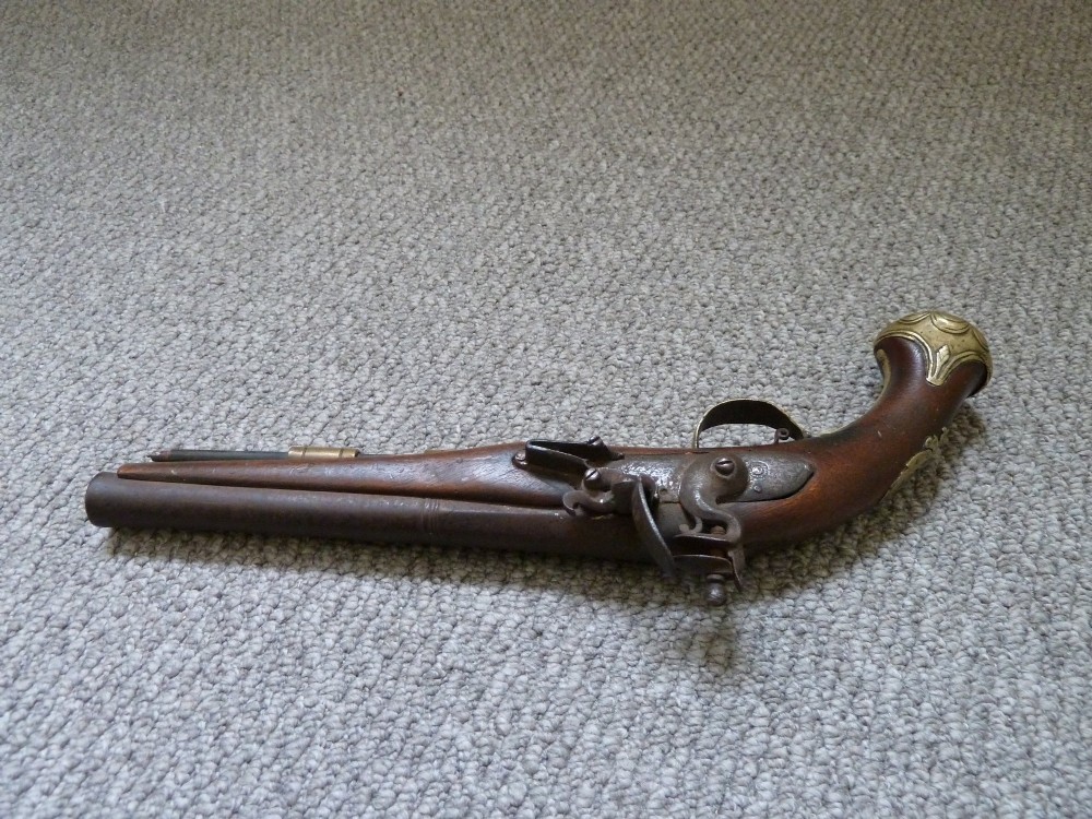 An 18th-century flintlock pistol featuring a carved dark walnut stock, engraved brass butt cap, brass ramrod pipes, and an iron lock mechanism. View XII
