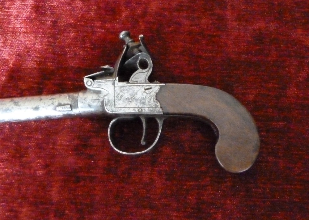 An 18th-century Georgian flintlock pocket pistol featuring an engraved steel lock mechanism, short round barrel, and smooth wooden grip. View VI