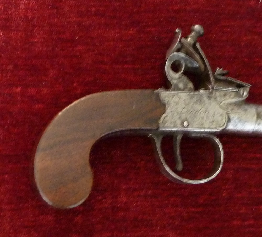 An 18th-century Georgian flintlock pocket pistol featuring an engraved steel lock mechanism, short round barrel, and smooth wooden grip. View VII